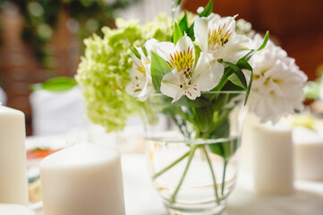 Obraz na płótnie Canvas Beautiful flowers in vase, close up. Festive table decorated with white and green composition, candles in the banquet hall. Newlyweds table in banquet area for wedding. Film noise
