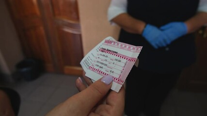 Woman gives ticket to taker in blue gloves in cinema hall