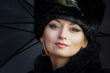 A beautiful girl in a historical retro dress against the background of an old steam locomotive at the station.