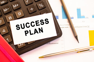 Text SUCCESS PLAN on white card with metal pen, calculator and financial charts.