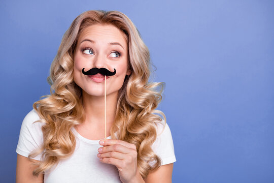 Photo of young attractive girl happy smile have fun look empty space hold paper mustache on stick isolated over blue color background