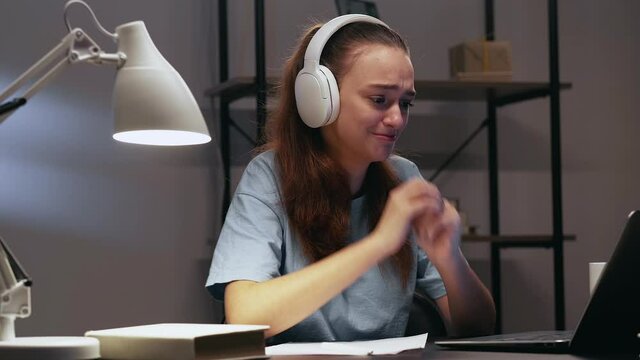Video call. Distance communication. Virtual meeting. Upset student girl in headphones missing family home happy to see speak share news online using laptop in dark dormitory room workplace in evening.
