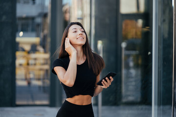 Fototapeta premium Portrait of a young brunette woman with headphones while walking