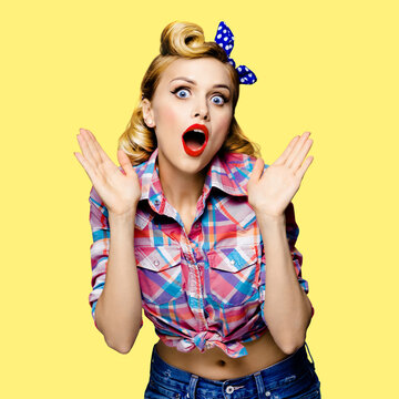 Unbelievable news! Excited surprised, very happy blondy hair woman. Pin up syle girl with opened mouth and raised hands. Retro and vintage concept. Yellow background. Square composition.