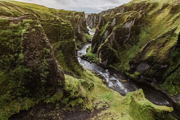 A gorge and a canyon Fjadrargljufur in Iceland. Panoramic photography. The concept of postcards and travels. Green grass and picturesque cliffs. Icelandic nature.