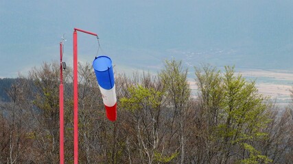 wind sock - red , blue and white pointer indicating strength and direction of the wind against the blue sky