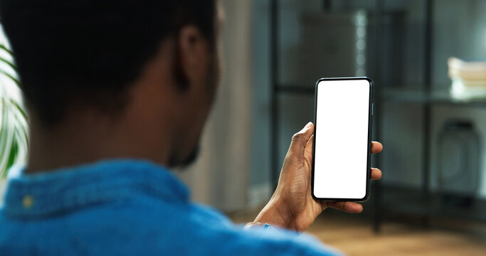 Close Up Of African American Man Holding New Black Smartphone With Blank Screen In Hands. Mobile Phone With Blank Copy Space Screen For Your Text