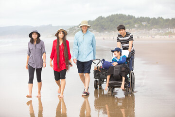 Caucasian father with four biracial children walking on beach