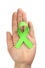 Green ribbon in hand isolated on white as a symbol of disease awareness, organ transplant. Vertical orientation