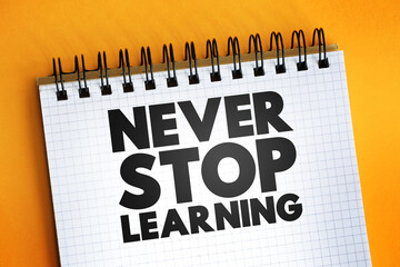 Never Stop Learning text quote on notepad, concept background.
