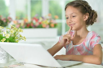 thoughtful cute girl using laptop at home