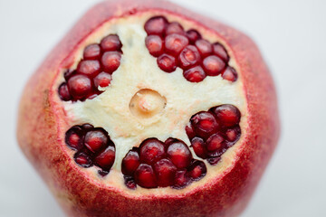 Red cut pomegranate isolated on white background. Pomegranate granules are bright red. Top view,...