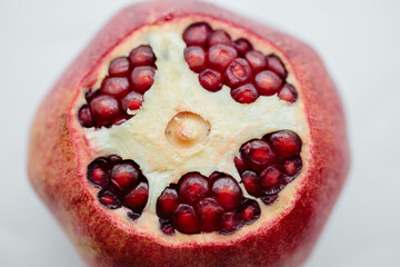 Red cut pomegranate isolated on white background. Pomegranate granules are bright red. Top view, close-up.