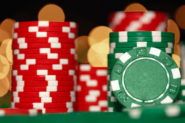 Fototapeta premium Stack of casino chips on green table against bokeh background
