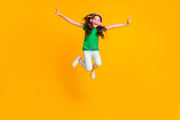 Fototapeta na wymiar Full size photo of happy excited crazy smiling funky girl jumping listen music in earphones isolated on yellow color background
