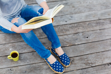 hipster girl reading book on a wooden floor