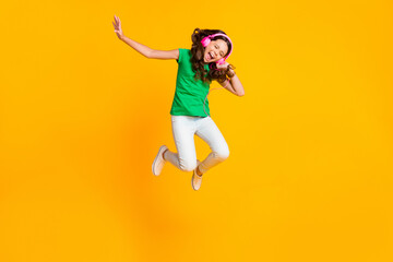 Fototapeta na wymiar Full size photo of happy cheerful excited crazy girl jumping listening music in headphones isolated on yellow color background