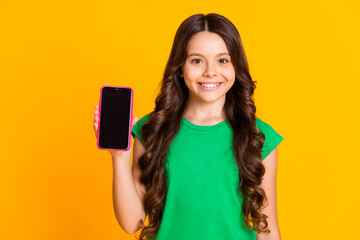 Photo of happy cheerful good mood lovely girl showing smartphone display touchscreen isolated on yellow color background