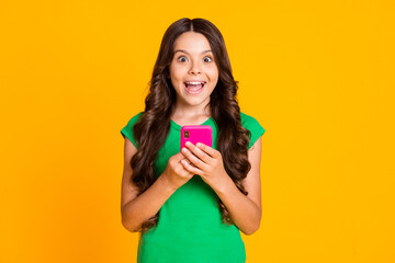 Photo of happy cheerful smiling lovely crazy girl see post comment in smartphone isolated on yellow color background