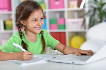 Portrait of concentrated little girl with laptop studying