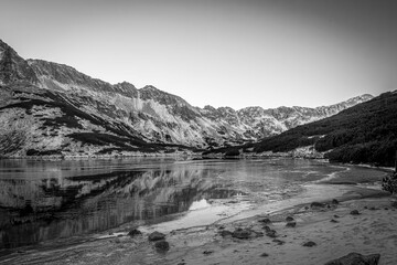 Black and white view of Dolina Pięciu Staw&oacute;w Polskich, Tatra Mountains, Poland. A valley with a lake which is starting to freeze. Selective focus on the rocks, blurred background.