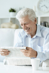 Fototapeta na wymiar Senior man reading newspaper at home