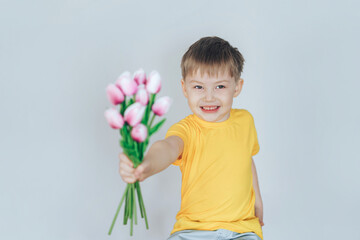 Boy standing in front of white background and holding tulips in his hands