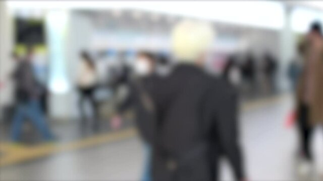 Blurred shot of people with mask walking through Hiroshima station in Japan. 4K. March 22, 2021