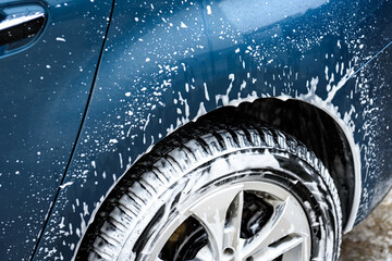 Fototapeta na wymiar High pressure automobile cleaning with foam in car wash.