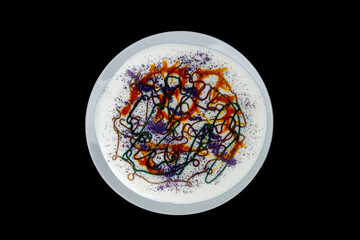 An abstract palette of a variety of materials. Preparation of material for contemporary creativity.On a dark background, a plate with white paint and multicolored shiny lines.