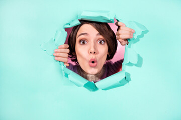 Portrait of impressed pretty girl arms touch hole looking from torn paper isolated on turquoise color background - obrazy, fototapety, plakaty
