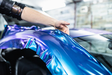 Car wrapping specialist putting vinyl foil or film on car. Selective focus.