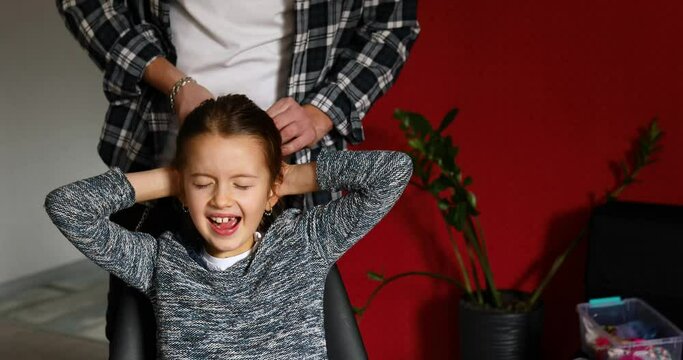 Father combing, brushing his daughter's hair at home, child making faces about hair pulling, angry girl feeling pain, family moments, spending time together.