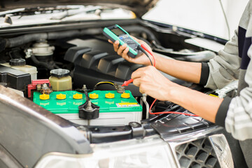 A technician is checking the car battery for availability.;