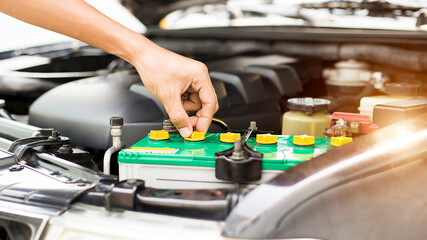 Automobile mechanic repairman checking a car engine with inspecting writing to the clipboard the checklist for repair machine, car service and maintenance.