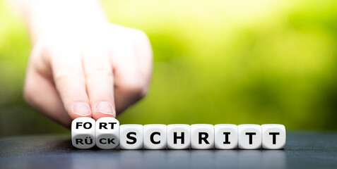 Hand dreht Würfel und ändert das Wort Rückschritt in Fortschritt.