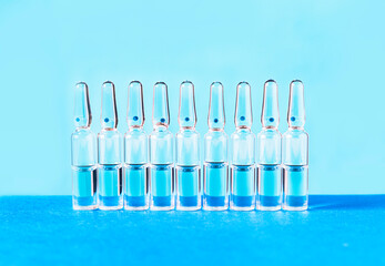 Medical ampoules for injection on a blue background. Scattered glass ampoules with medicine on the table. Medicines and disease treatment