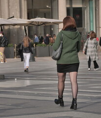 Fashionable woman walking in miniskirt and pantyhose in Duomo square, Milan, Lombardy, Italy.