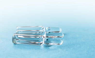 Medical ampoules for injection on a blue background. Scattered glass ampoules with medicine on the table. Medicines and disease treatment