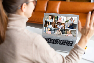 Webinars, online conference, video meeting. A young woman is using app on laptop for video connect with a many people at same time together at office. Distant work concept