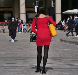 Fashionable woman posing in miniskirt and black pantyhose in Duomo square, Milan, Lombardy, Italy.