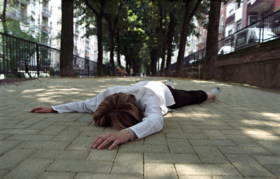 unrecognizable woman fell to the ground in the street 