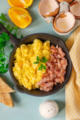 Skillet of scrambled eggs with bacon lardons for breakfast