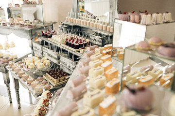 Beautiful bright buffet with many sweet snacks a candy bar on a white table and is waiting for guests at the celebration. Wedding pastries on a mirror tray. Sweet candy bar on table