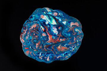 Acrylic blue and red paint with glitters is poured on a black background. An abstract painting with a multi-colored surface. Search for a palette for creativity.