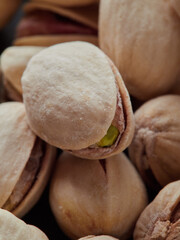 Fried fresh pistachios are scattered on a black background close-up. Top view. Space for the text. Copy space