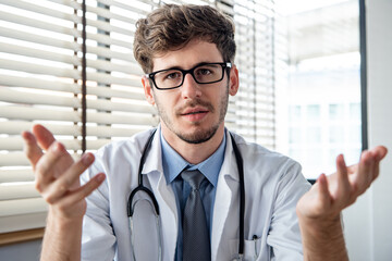 Young male doctor looking at camera explaining and talking with patient online via video calling, distance consulting service concepts