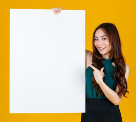 Cute and pretty curly hair Asian female brunette holding white  blank board poses to camera with a joyful for advertising and banner use purpose, studio shot isolated on bright yellow background
