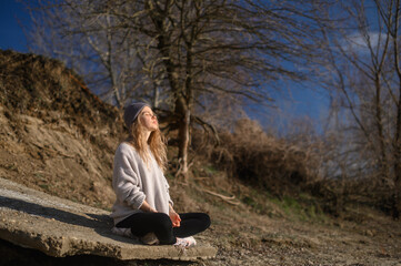 Naklejka na ściany i meble Practice of meditation and interaction with nature. Girl near river
