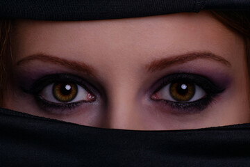Gorgeous female eyes and face covered with black scarf